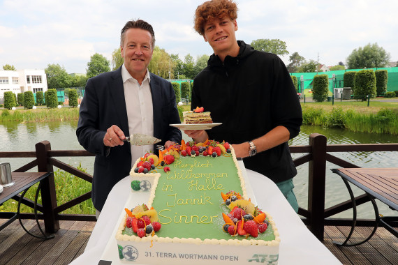 Turnierdirektor Ralf Weber (links) begrüßt den Italiener Jannik Sinner in HalleWestfalen und beglückwünscht ihn mit einer Torte zur Nummer eins der Welt.